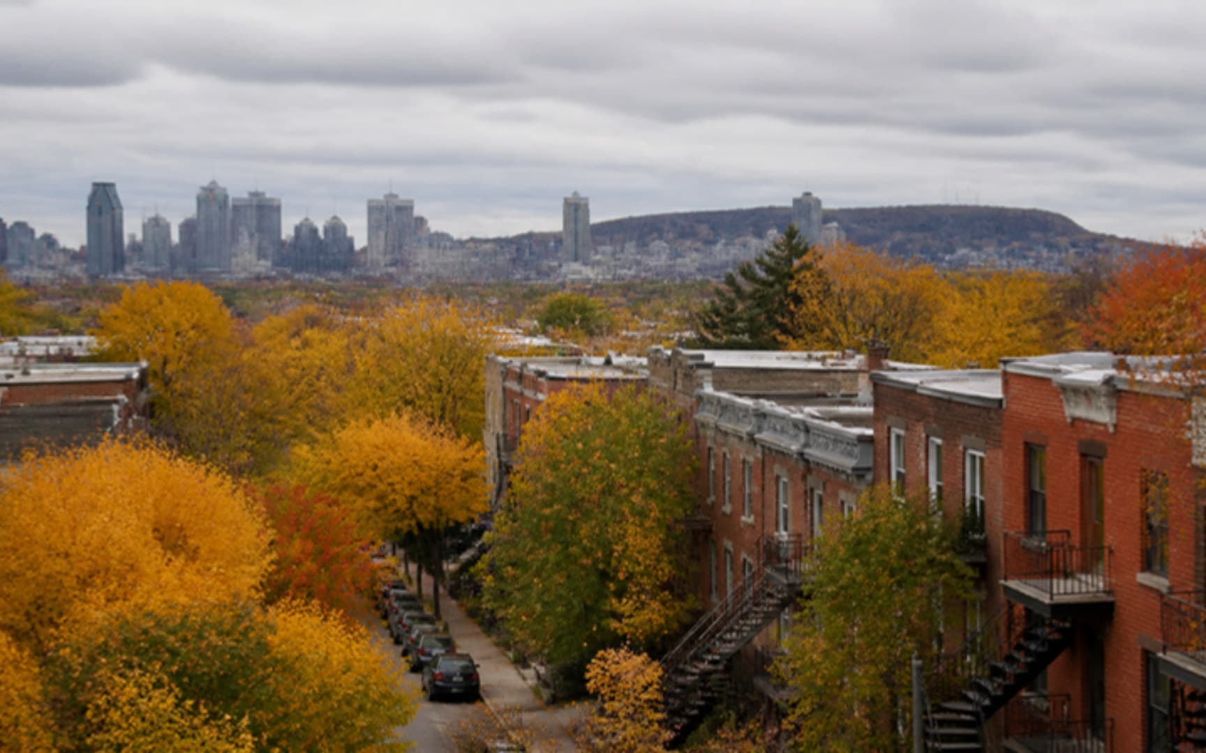 Quartier résidentiel montréalais en automne, plex en brique avec escaliers extérieurs et arbres dorés, centre-ville au loin — illustration générée par IA