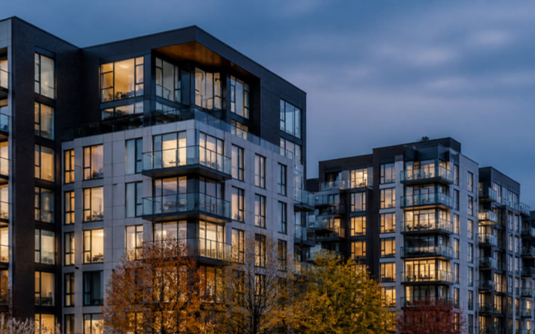 Immeubles de condos contemporains avec balcons vitrés au crépuscule, fenêtres éclairées et arbres d'automne — illustration générée par IA